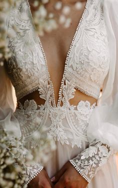 the back of a woman's wedding dress, with white flowers in the background