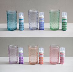 there are many different colored glass jars on the table and in front of each other