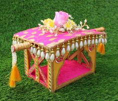 a pink and gold decorated table with flowers on it in the middle of green grass