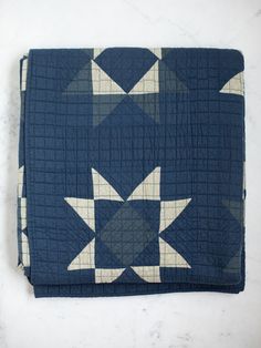 a blue and white quilted blanket with stars on it, sitting on a marble surface