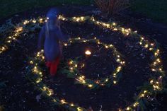 a person standing in the middle of a circle with christmas lights on it's sides