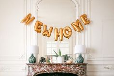 a fireplace with gold balloons that spell out the word me and some plants in front of it