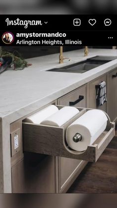 two rolls of toilet paper are sitting on the pull out drawer in this kitchen counter