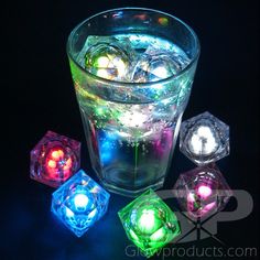 four glowing lights in a glass filled with ice cubes