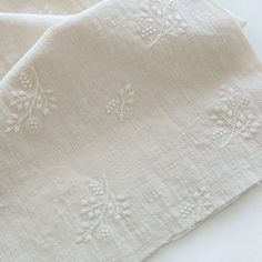 two white linen napkins with embroidered flowers on them