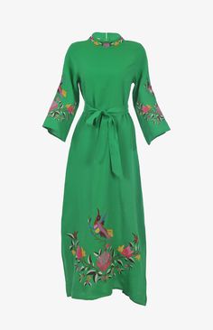 a green dress with flowers and birds on the sleeves, tied at the waistline