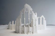 a model of a building made out of white bricks on snow covered ground with dark sky in the background