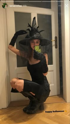 a woman dressed up as a witch holding a cell phone in her hand and sitting on the floor