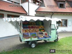 a green and white truck parked in front of a building with lots of food on it