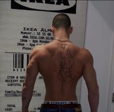 a man with tattoos on his back standing in front of a sign that says ikea