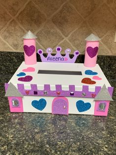 a pink and purple princess castle made out of cardboard with glitter hearts on the top