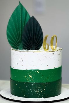 a white and green cake with gold numbers on top