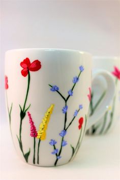 two coffee cups with flowers painted on them