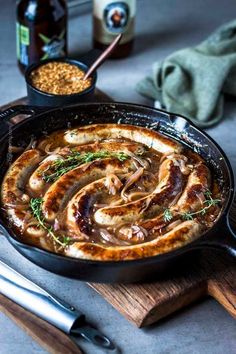 a skillet filled with meat and vegetables sitting on top of a wooden cutting board