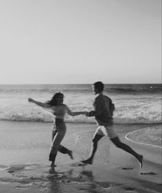 black and white photograph of two people running on the beach