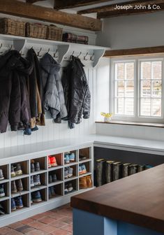 several coats hanging on the wall in a room with brick flooring and white walls