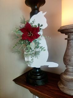 a white rabbit with red flowers on top of a wooden table next to a lamp