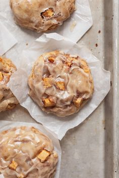 four cinnamon rolls with icing on top of parchment paper