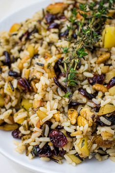 a white plate topped with rice covered in nuts and dried cranberry toppings