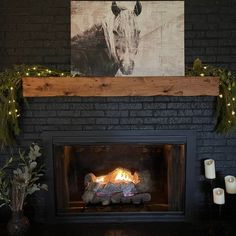 a fire place with a cow painting on the wall and candles in front of it