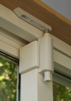 an open window with a white roller on it's side and trees in the background