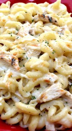 a red plate topped with pasta covered in chicken