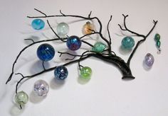 a tree with many different colored glass balls hanging from it's branches on a white wall