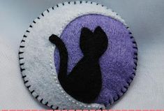 a black cat sitting on top of a purple and white patch