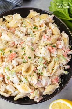 a bowl filled with pasta salad next to lemon wedges