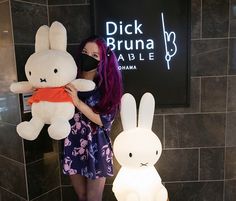 a woman with purple hair holding two stuffed animals