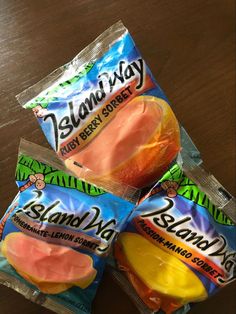 three bags of island bay candy sitting on top of a wooden table next to each other