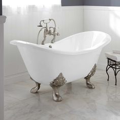 a white bath tub sitting in a bathroom next to a toilet and sink with an ornate faucet