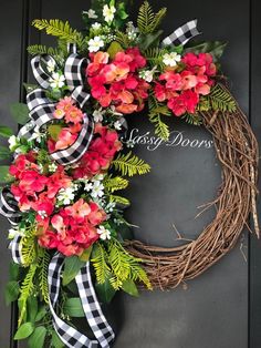 a wreath with red flowers and greenery on the front door