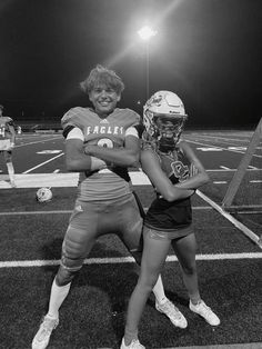 two female football players posing for a photo on the field at night with their arms around each other