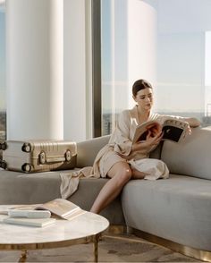 a woman sitting on a couch reading a book