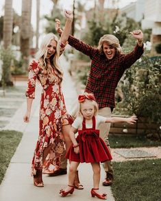 two adults and a child are posing for a photo in front of the camera with their hands up