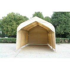 a large beige tent sitting on top of a cement floor next to trees and bushes