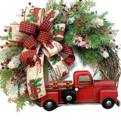 a christmas wreath with a red truck and evergreens