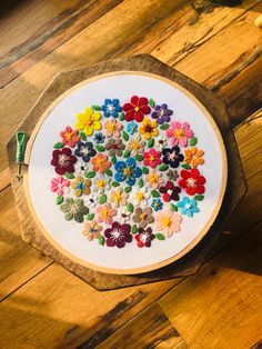 an embroidery kit with flowers on it sitting on top of a wooden table