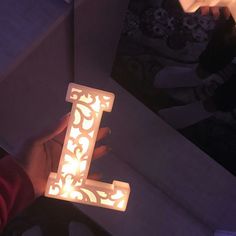 a person holding a lit candle in the shape of a letter l on a table