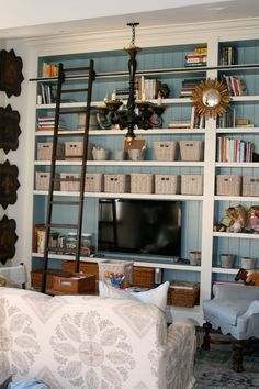 a living room filled with furniture and a flat screen tv mounted on a wall next to a bookshelf