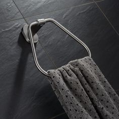 a towel hanging on the wall next to a metal holder with a hook in it