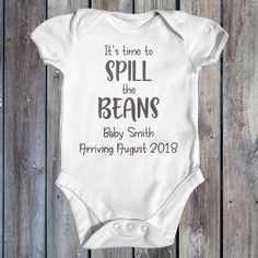 It's Time To Spill The Beans Baby Bodysuit. Looking for an adorable and personalised pregnancy reveal? Well, this cute little bodysuit is the PERFECT for you! Surprise your family and friends with the news of your pregnancy - give them one of these bodysuits that can also be used as a photo prop. This bodysuit features the words "It's Time To Spill The Beans" and can be personalised to your requirements. When submitting your order please include  - Surname, Month and Year of baby's arrival. Want Personalized Fitted Onesie For Gender Reveal, Personalized Cotton Onesie For Gender Reveal, Fitted Bodysuit For Family Matching At Gender Reveal, Family Matching Custom Print Onesie For Gender Reveal, White Onesie For Gender Reveal With Funny Text, Pregnancy Announcement Onesie, Pregnancy Announcements, Baby Arrival