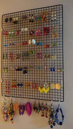 there are many earrings hanging on the wall next to each other and one has a wire rack holding them