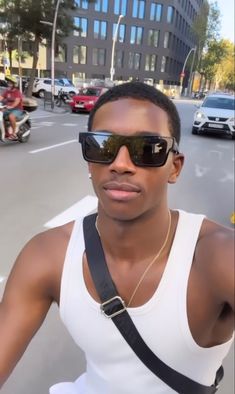 a man wearing sunglasses and a white tank top