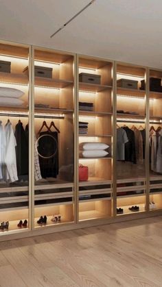 a walk in closet with lots of clothes on shelves and lights above the doors that illuminates light