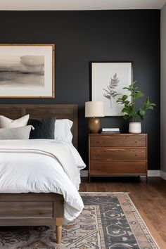 a bedroom with black walls, white bedding and wooden furniture is pictured in this image