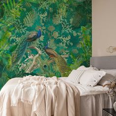 there is a bed with pillows and blankets on it in front of a peacock wall mural