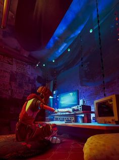 a man sitting on the floor in front of a tv playing video games at night