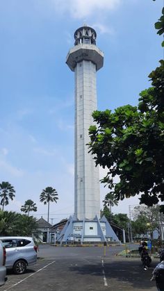 a tall white tower sitting next to a parking lot